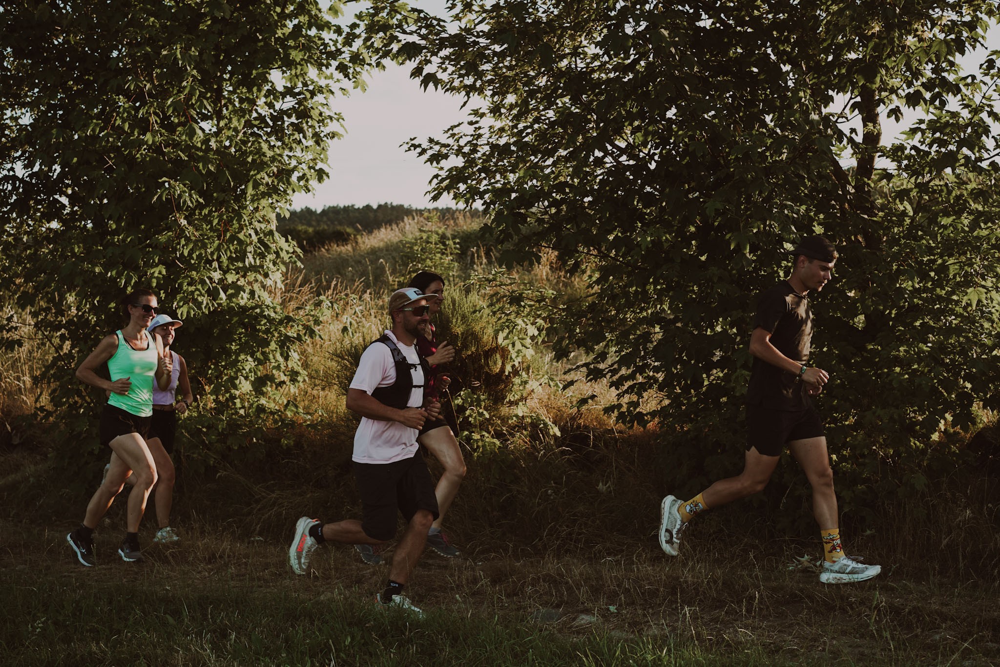Groupe de coureurs traversant un chemin forestier en lumière dorée